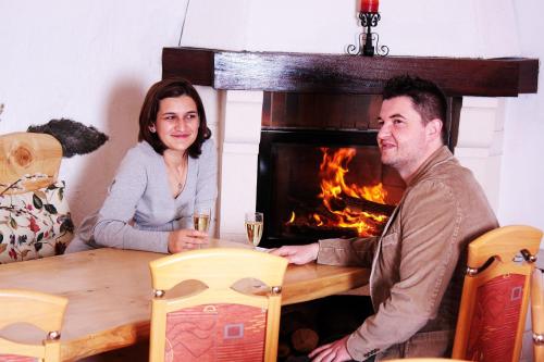 a man and woman sitting at a table in front of a fireplace at Maurushaus in Füssen