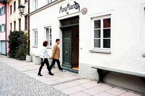 two people walking down a sidewalk next to a building at Maurushaus in Füssen