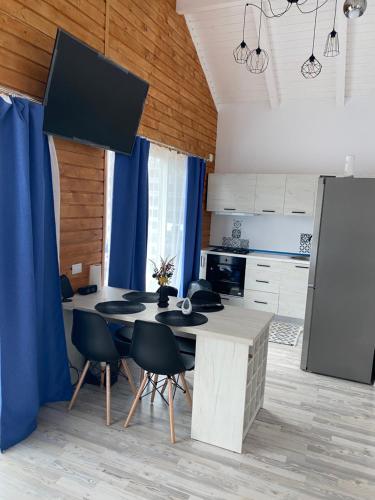 a kitchen with a table and chairs and blue curtains at Cabana EvAy in Ocnele Mari