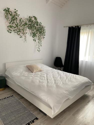 a white bed in a bedroom with a plant on the wall at Cabana EvAy in Ocnele Mari