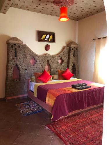 a bedroom with a king sized bed with red pillows at Riad Moha in Merzouga