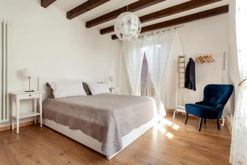a white bedroom with a bed and a blue chair at A central quiet place in Verbania in Verbania