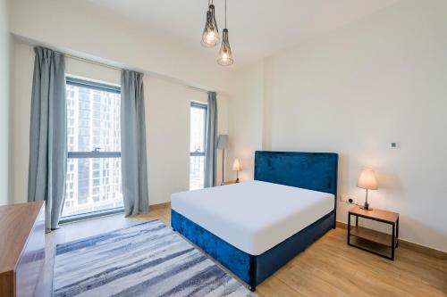 ドバイにあるExpo Village Serviced Apartmentsの大きなベッドと2つの窓がある寝室