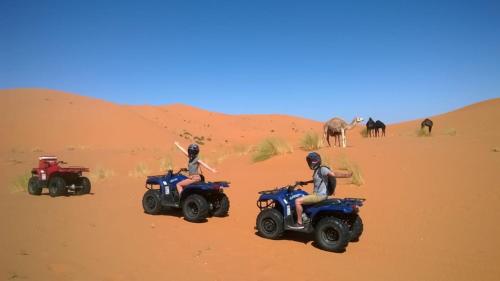 three people riding on atvs in the desert at Riad Moha in Merzouga