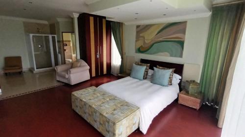 a bedroom with a large white bed and a chair at Castellon Boutique Hotel in Table View