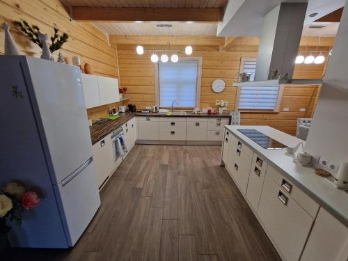 a large kitchen with white appliances and wooden walls at Baložu rezidence in Jūrmala