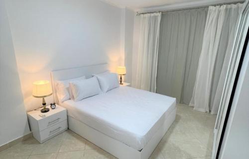 a white bedroom with a white bed and two lamps at The View 23 - B2 in Sharm El Sheikh