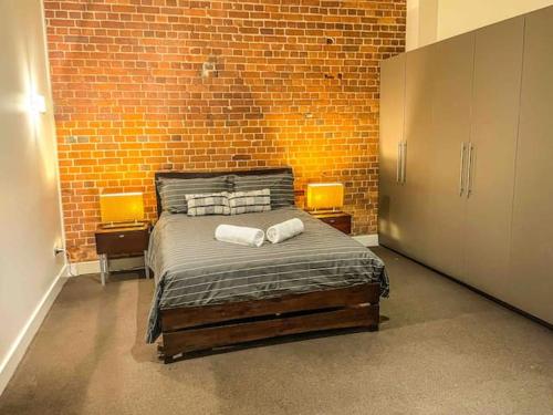 a bedroom with a bed and a brick wall at Townsville Central Apartment @ Flinders Street in Townsville