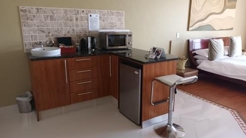 a kitchen with a counter with a microwave and a bed at Castellon Boutique Hotel in Table View