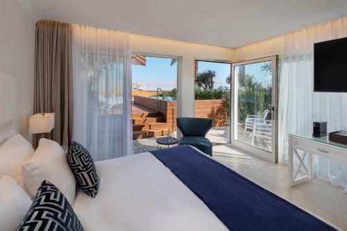 een slaapkamer met een bed en een balkon met een televisie bij Herbert Samuel Milos Dead Sea in Ein Bokek