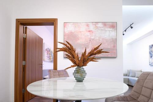 a white dining room with a table with a plant on it at Dedinje apartment in Belgrade