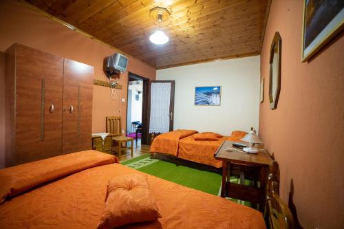 a bedroom with two beds and a table and a desk at Mprizis Rooms in Elati Trikalon