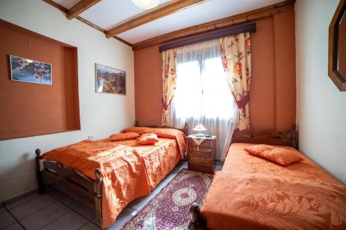 a bedroom with two beds and a window at Mprizis Rooms in Elati Trikalon