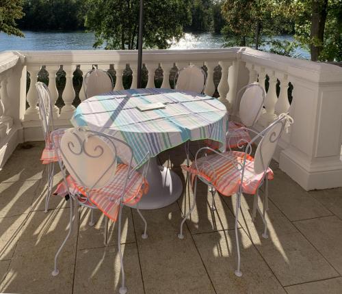 a table with chairs and an umbrella on a porch at La Grande Maison in Seine-Port