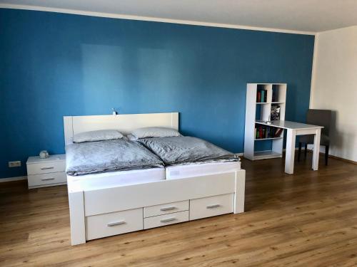a bedroom with a white bed and a blue wall at Ferienwohnung am Teutoburger Wald in Berghagen