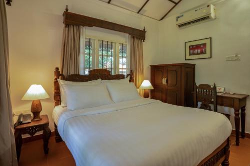 a bedroom with a large white bed and a window at MAI HOUSE HERITAGE HOTEL in Fort Kochi