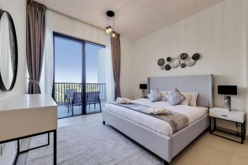 Habitación blanca con cama y balcón. en Primestay - Nasayem Avenue in Mirdif Hills, en Dubái