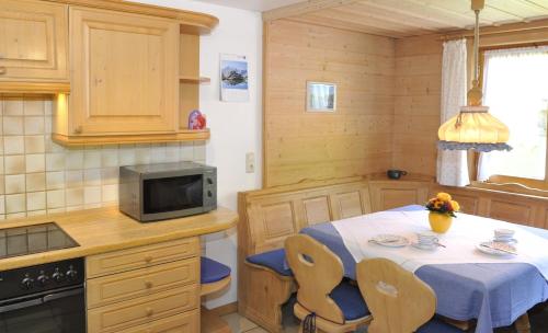 a kitchen with a table with chairs and a microwave at Gschwenderhaus Ferienwohnungen in Oberstdorf