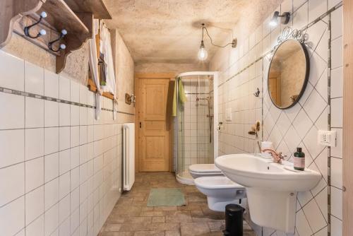 łazienka z 2 toaletami, umywalką i lustrem w obiekcie Baita Al Rossat w mieście Sant’Orsola