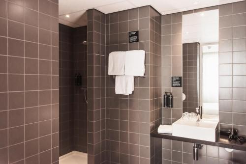 ein Bad mit einem Waschbecken und einer Dusche mit einem Spiegel in der Unterkunft Conscious Hotel Vondelpark in Amsterdam
