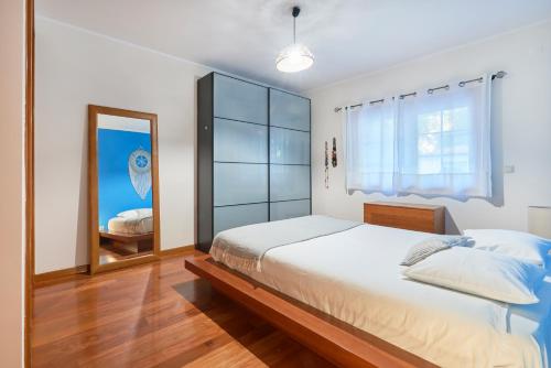 a bedroom with a large bed and a mirror at Sunny apartament at Carcavelos Beach, by TimeCooler in Carcavelos