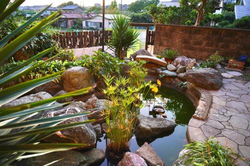 un jardin avec un étang agrémenté de plantes et de rochers dans l'établissement nostalgiaノスタルジア, à Yokosuka