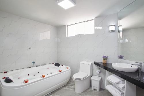 e bagno bianco con vasca, servizi igienici e lavandino. di Natura Inn Hotel ad Arequipa