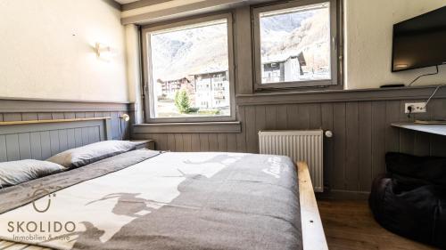 a bedroom with a bed and two windows at Haus Camillo in Saas-Fee