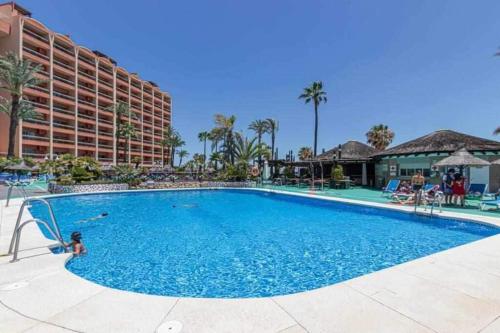 a swimming pool at a resort with a hotel in the background at 797 Holiday Rentals- Apartamento en Hotel Sunset Beach frente al mar in Benalmádena