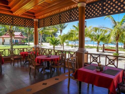 a restaurant with tables and chairs and palm trees at The Sunset Beach Resort - Koh Kho Khao in Ko Kho Khao