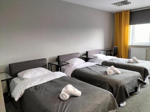 a room with three beds with towels on them at Hotel ŚWIT in Krakow