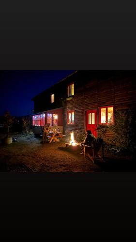 a person sitting around a fire in front of a building at Gîte Ranch Le Serpolet in Les Angles