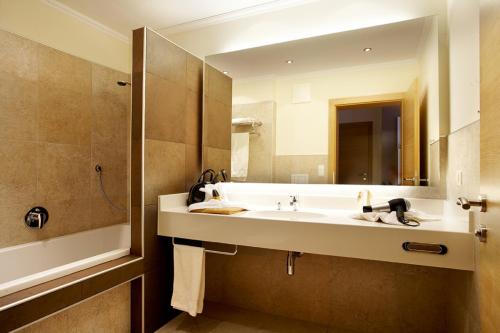 baño con lavabo y espejo grande en Sonnblick Apartments und Zimmer - Nationalpark Sommercard inklusive, en Hollersbach im Pinzgau