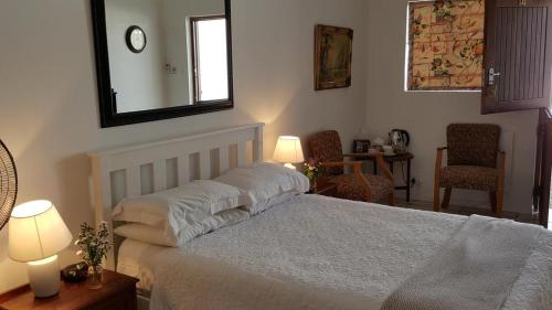 a bedroom with a bed with two lamps and a mirror at Camdeboo Cottages in Graaff-Reinet