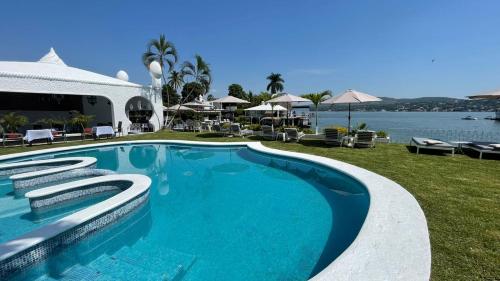 a large blue swimming pool next to a body of water at Marina Palace Teques in Tequesquitengo