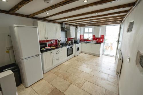 a kitchen with a white refrigerator and a tile floor at Quinta Cottage in Soutergate