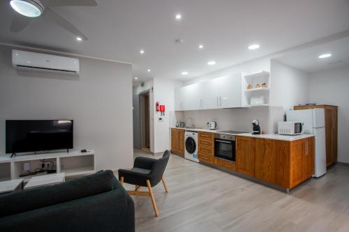 een woonkamer met een bank en een keuken bij The Three Trees Apartments in Sliema