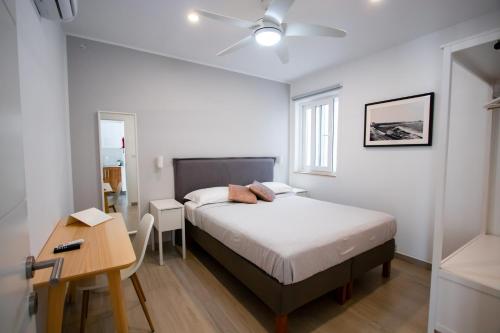 um quarto com uma cama, uma secretária e uma ventoinha de tecto em The Three Trees Apartments em Sliema