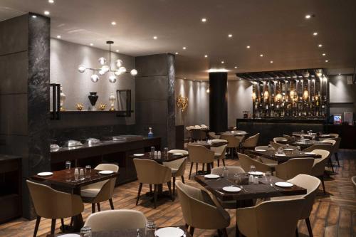 a restaurant with tables and chairs and a bar at The Cindrella Hotel in Siliguri