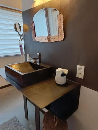 La salle de bains est pourvue d'un lavabo noir et d'un miroir. dans l'établissement Loft, parking privé, terrasse, entrée indépendante, à Liège