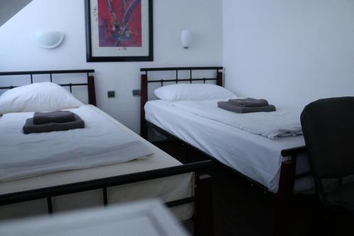 two twin beds in a room with a chair at Hotel Berliner Hof in Düsseldorf