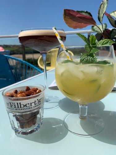 a drink sitting on a table next to a bowl of nuts at Porth Beach Hotel in Newquay