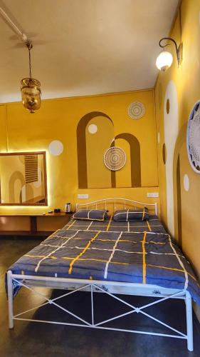 a bed in a room with a yellow wall at Pappi Chulo Vagator in Vagator