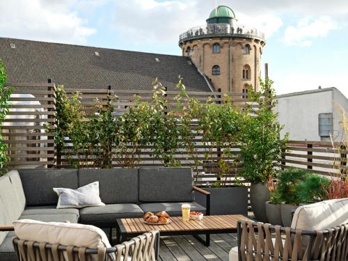 a patio with a couch and a table and a building at Apēron Apartment Hotel in Copenhagen