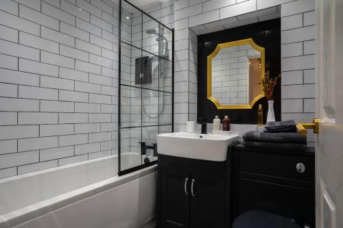 uma casa de banho em preto e branco com um lavatório e um espelho em The City Escape - 5* stay in the heart of Glasgow! em Glasgow