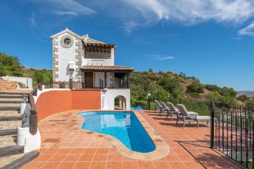 una piscina con sillas y una casa en La Casa de Alejandro, en El Chorro