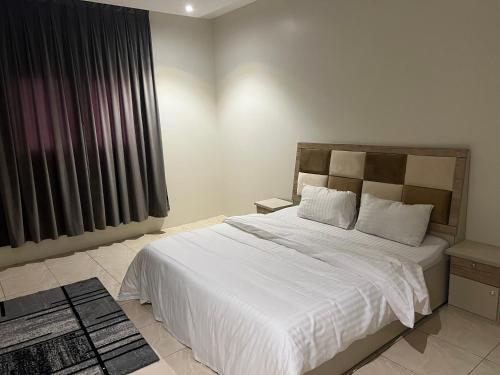 Un dormitorio con una gran cama blanca y una ventana en شقق قمة الرفاء للوحدات السكنيه, en Riad