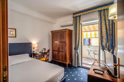 um quarto com uma cama, uma secretária e uma janela em Hotel Napoleon em Roma