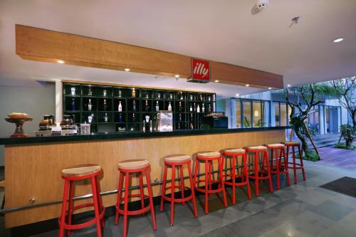 a bar with red stools in a restaurant at Hotel NEO+ Kuta Legian by ASTON in Legian