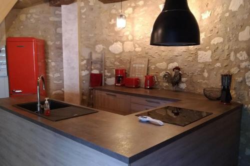eine Küche mit einer Spüle und einem roten Kühlschrank in der Unterkunft La tour du logis, gîte 4 * à 15 min du Futuroscope 